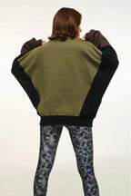 Person wearing a green and black jacket with camouflage pants on a white background