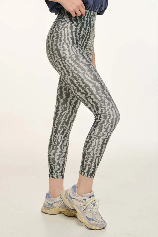 Person wearing patterned leggings and sneakers on a white background
