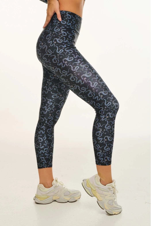 Person wearing dark blue leggings with a pattern on a white background