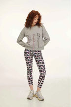 Person wearing a gray sweatshirt and patterned leggings on a white background
