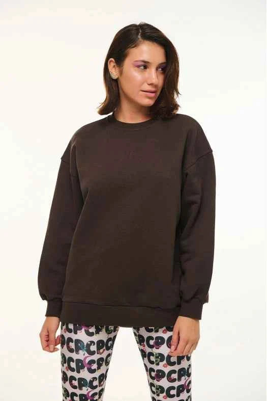 Woman wearing a dark brown sweatshirt and patterned pants on a white background