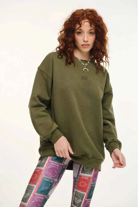 Person wearing an olive green sweatshirt and colorful leggings on a white background