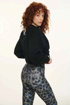 Person wearing a black jacket and camouflage pants on a white background