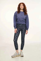 Woman wearing a blue sweatshirt and patterned leggings on a white background