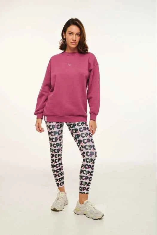 Person wearing a pink sweatshirt and patterned leggings on a white background