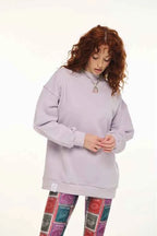 Person wearing a light gray oversized hoodie and colorful patterned leggings on a white background