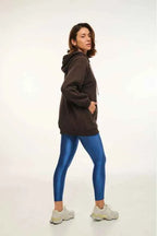Woman wearing a brown hoodie and blue leggings on a white background