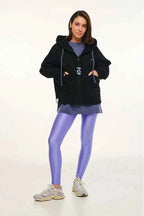 Person wearing a black hoodie, purple leggings, and sneakers on a white background