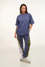 Person wearing a blue oversized t-shirt and tracksuit with a white background