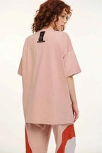 Person wearing a light pink oversized t-shirt and pants with red and white accents on a white background