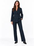 A woman modeling a dark navy blue double-breasted blazer and matching wide-leg trousers, paired with black ankle boots, against a plain white studio background.