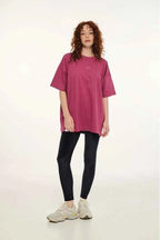 Person wearing a pink oversized t-shirt and black leggings on a white background
