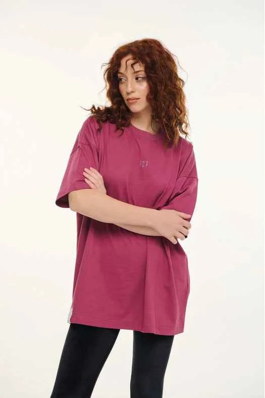 Woman wearing a pink tunic over black pants on a white background