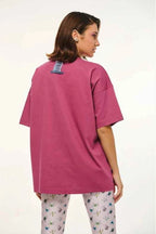 Person wearing a pink oversized t-shirt and patterned pants on a white background