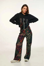 Person wearing a black hoodie and colorful patterned pants on a white background