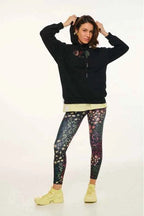Person wearing a black hoodie with floral design, a light-colored shirt, and colorful patterned leggings on a white background.