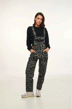 Person wearing camouflage overalls and black top on a white background