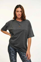 Woman wearing a dark gray oversized t-shirt and patterned leggings on a white background