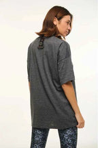 Person wearing a long gray shirt with a white background