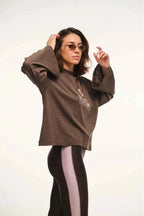 Person wearing a brown oversized sweater and black leggings with white stripes on a white background