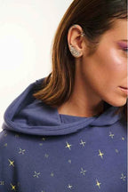 Person wearing a blue hoodie with star patterns and sparkling earrings.