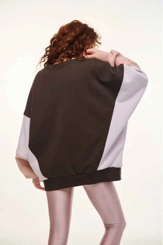 Person wearing a two-tone sweater with one sleeve black and the other white on a plain background