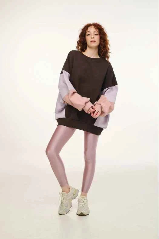 Woman wearing a black and gray sweater dress with sheer tights and sneakers on a white background