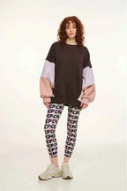 Person wearing a two-tone sweater and patterned leggings on a white background