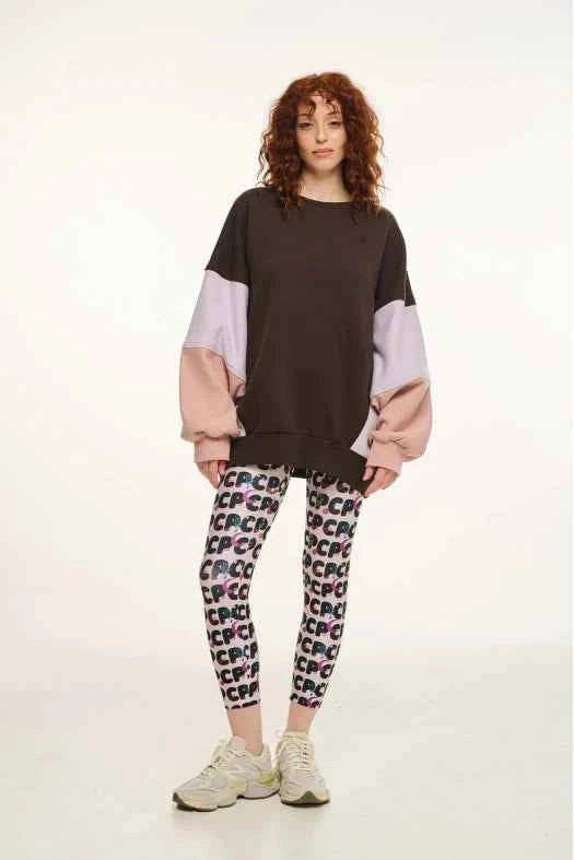 Person wearing a two-tone sweater and patterned leggings on a white background