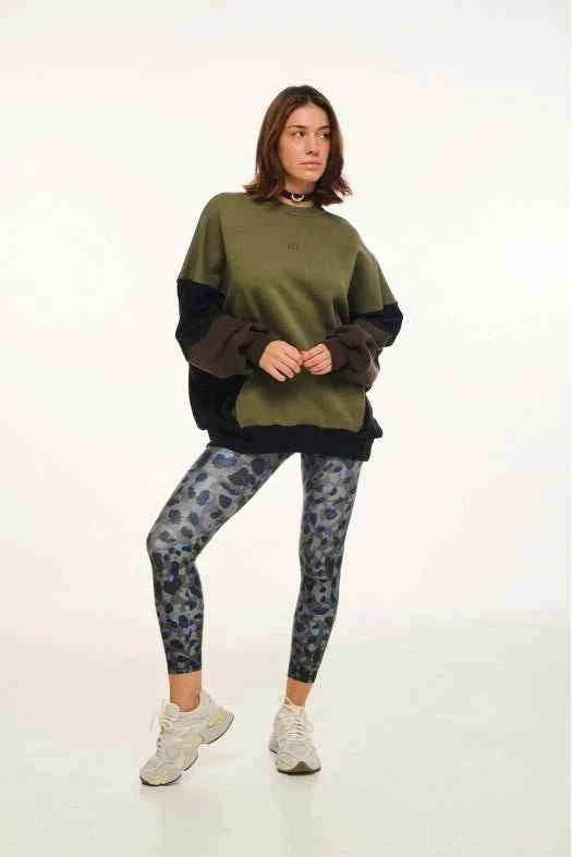 Person wearing a green sweater and patterned leggings on a white background