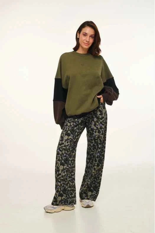 Woman wearing a green sweater and patterned pants on a white background
