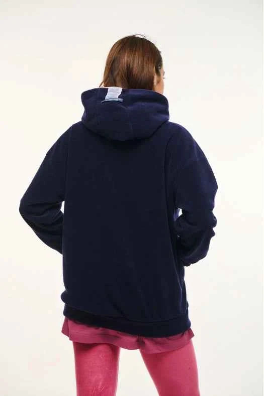 Person wearing a navy blue hoodie with a visible brand logo on a white background