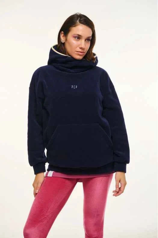 Woman wearing a navy blue hoodie and pink pants on a white background