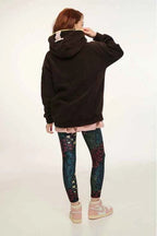 Person wearing a black hoodie and colorful leggings on a white background