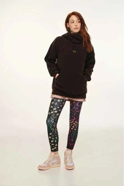 Person wearing a black hoodie and colorful leggings on a white background