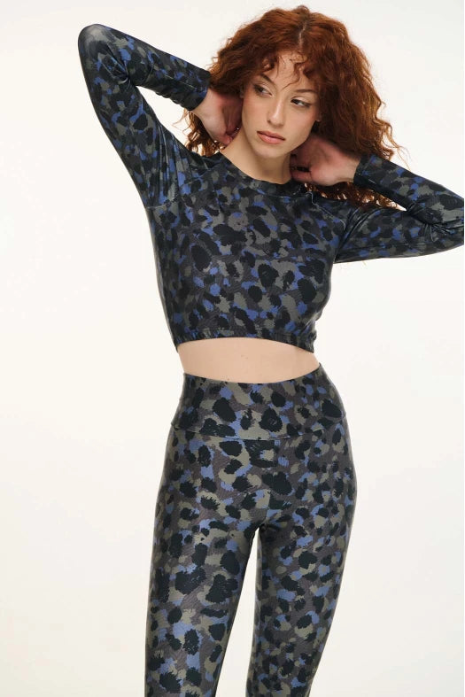 Woman wearing a blue and black patterned crop top and leggings on a white background