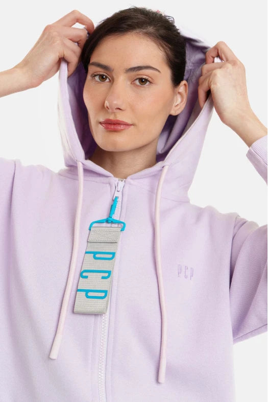 Woman wearing a light purple hoodie with a brand logo on a white background