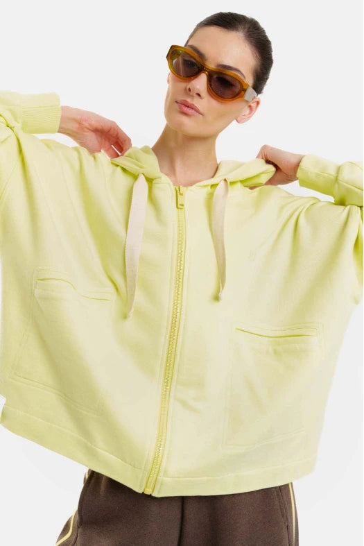 Person wearing a light yellow hoodie with a white background