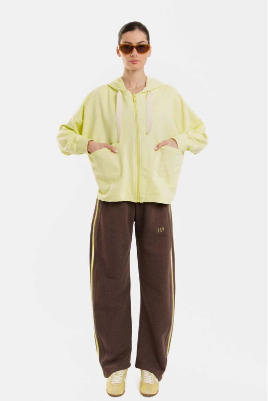 Person wearing a yellow hoodie and brown tracksuit with white stripes on a white background