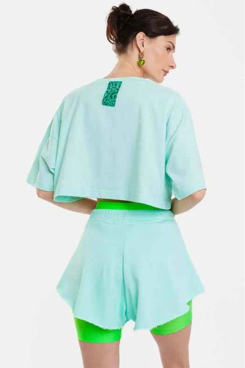 Woman wearing a light blue outfit with green accents on a white background