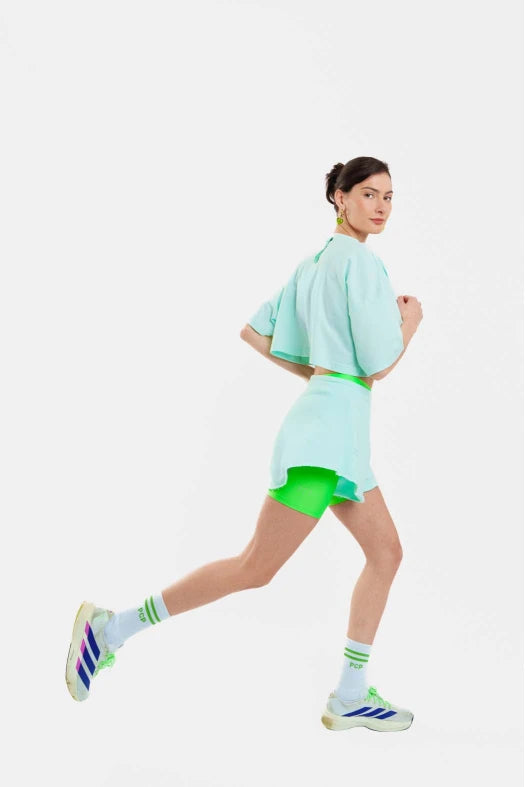 Person wearing a light blue outfit with green accents on a white background