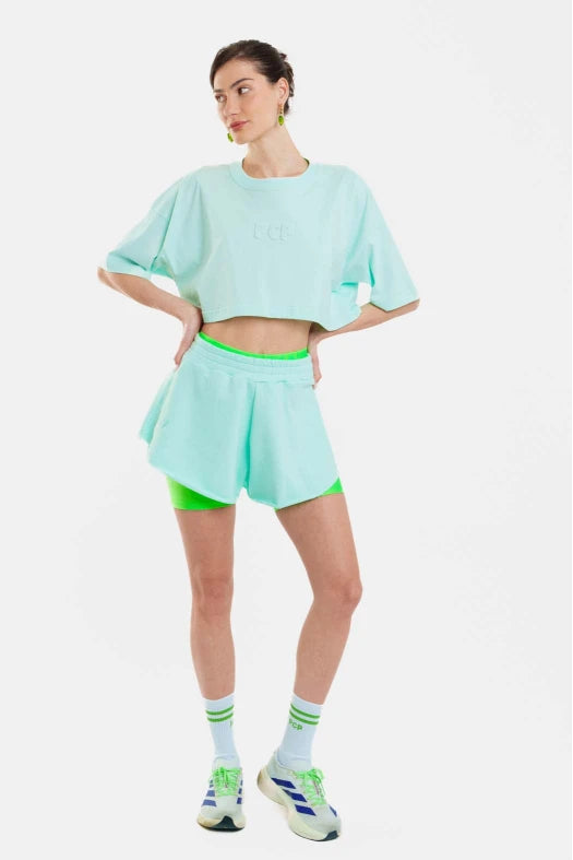 Woman wearing a light blue outfit with green accents on a white background