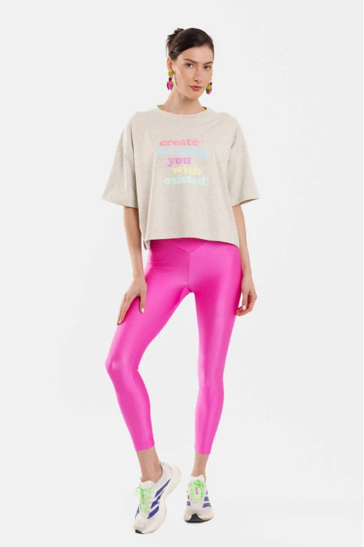 Woman wearing a gray oversized t-shirt and bright pink leggings on a white background