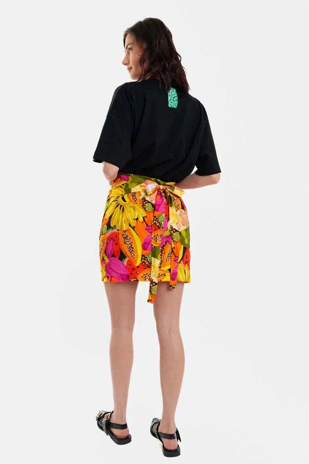 Woman wearing a black top and colorful floral skirt on a white background
