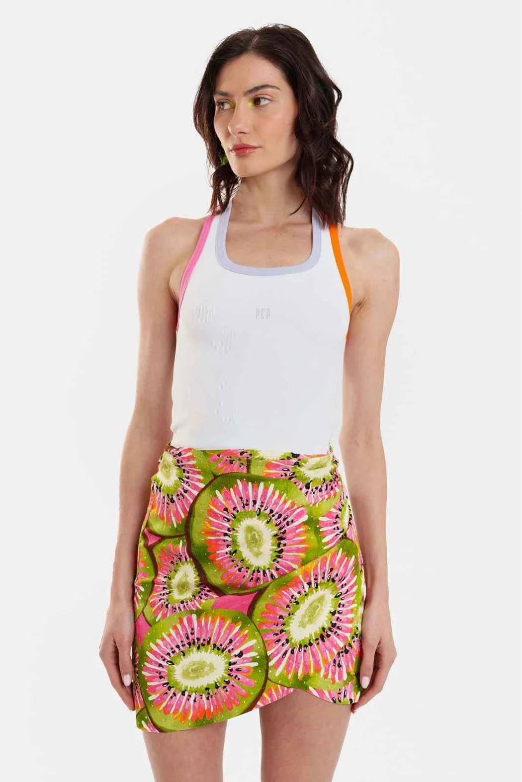 Woman wearing a white tank top and colorful skirt with a white background
