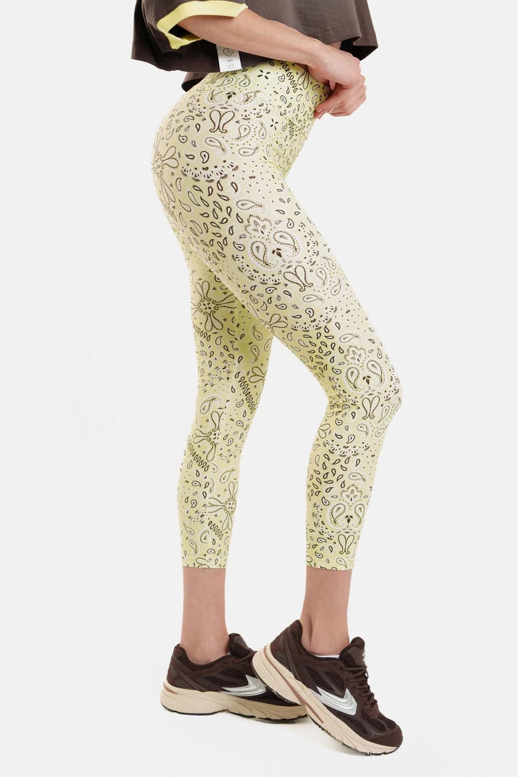 Person wearing light green leggings with a pattern on a white background
