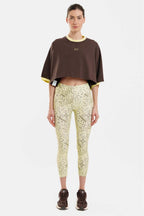 Person wearing a brown cropped top and patterned leggings on a white background