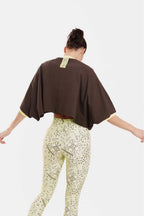 Person wearing a brown top and patterned pants on a white background