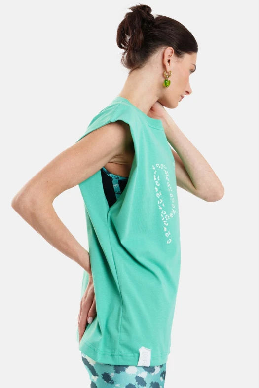 Woman wearing a green sleeveless top with text, standing against a white background