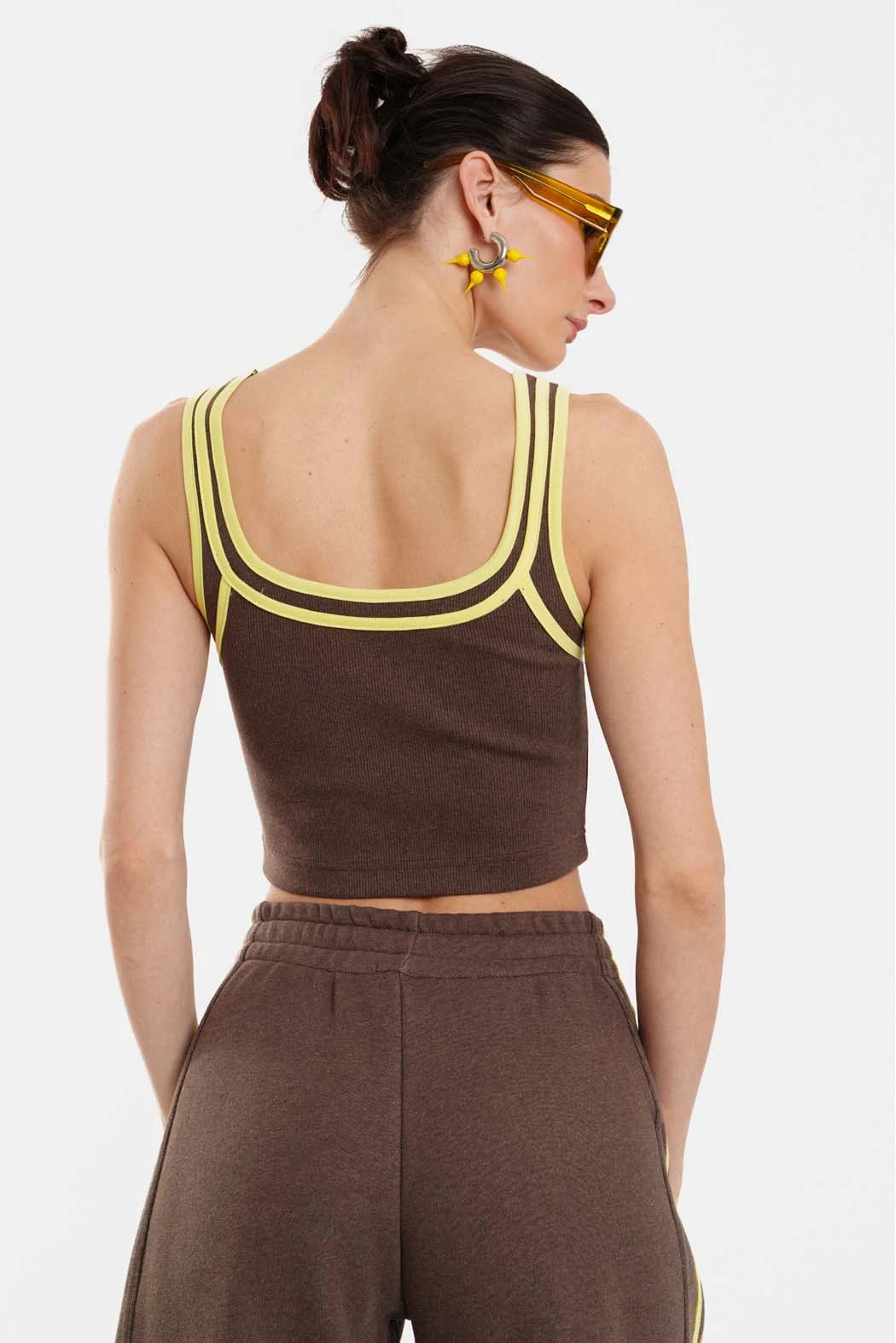 Woman wearing a brown crop top with yellow accents and matching pants on a white background